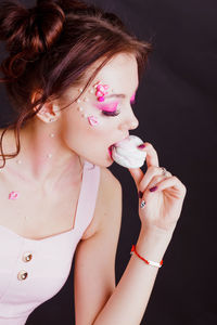 Close-up of beautiful young woman against black background