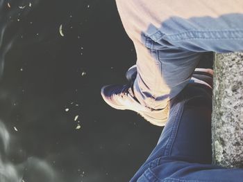 Low section of man sitting on cliff