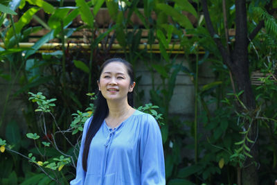 Smiling woman standing against plants