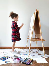 Side view of baby girl standing against wall