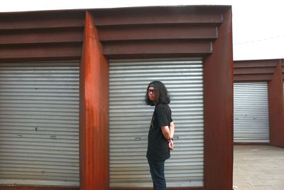 Full length portrait of young woman standing against building