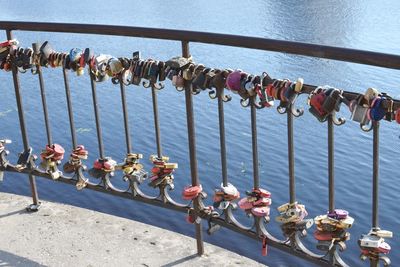 Padlocks hanging on railing against bridge