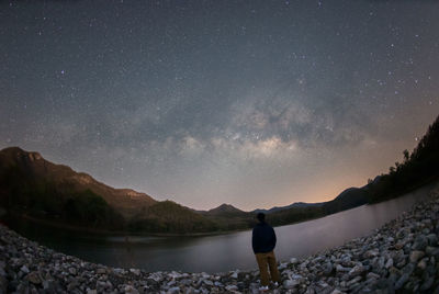 Rear view of man standing on mountain against sky at night