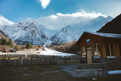 Houses on snowcapped mountain against cloudy sky