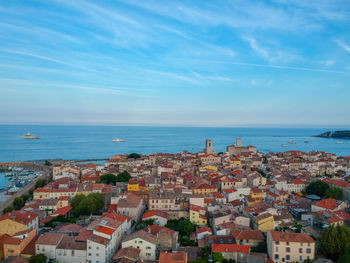 Aerial view of townscape by sea against sky