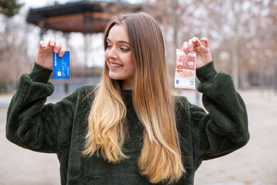 Portrait of smiling young woman holding camera