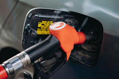 Fuel nozzle filling petrol into car tank at gas station.