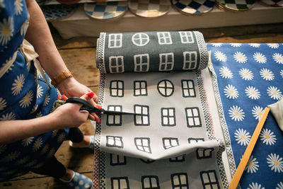 Midsection of woman cutting fabric swatch in shop