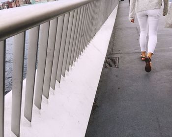 Rear view of woman walking on bridge by railing over canal