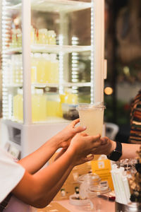 Woman hand passing a drink to a child in a shop.