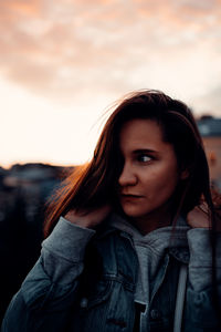 Portrait of beautiful young woman standing against sky during sunset