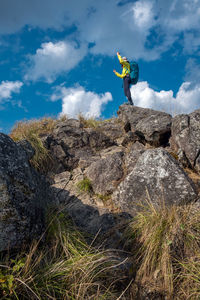 Low angle view of woman standing on mountain against blue sky