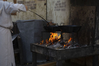 Man standing by fire on barbecue grill