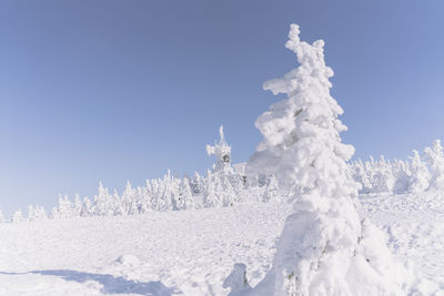 Snow covered land against clear blue sky