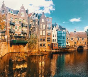 Buildings by river against sky in city