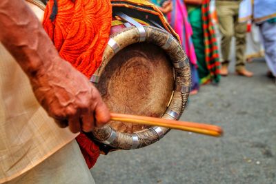Midsection of man playing drum on street
