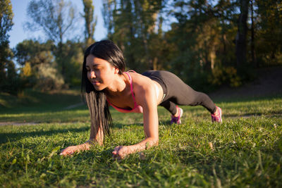 Young girl practices yoga in the park on the grass.