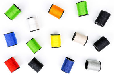 Directly above shot of colorful thread spools on white background