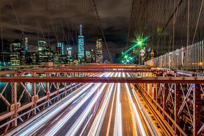 Light trails on brooklyn bridge against sky at night