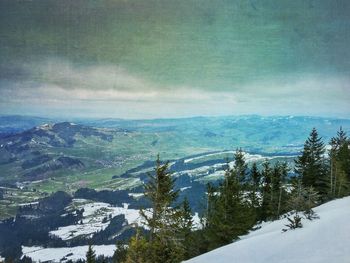 Scenic view of snow covered mountains against cloudy sky