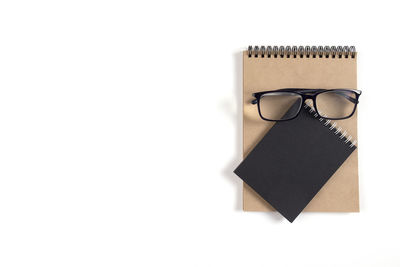 High angle view of eyeglasses on paper against white background