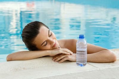 Beautiful woman resting head on hands in swimming pool