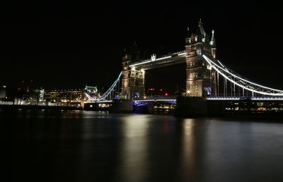 Illuminated bridge over river at night