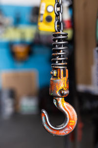 Metal hook with stains of paint hanging on blurred background of professional workshop