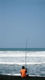Man fishing on beach against sky