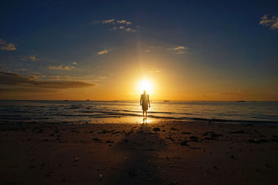 Silhouette man standing on beach against sky during sunset