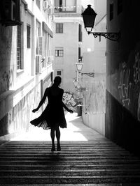 Full length of woman walking on street amidst buildings in city