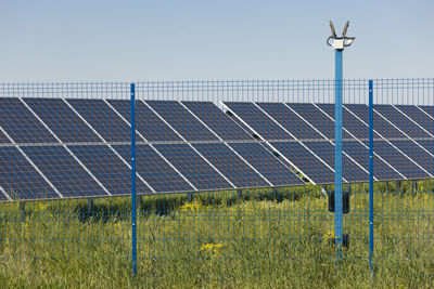 Low angle view of electricity pylon on field against clear sky