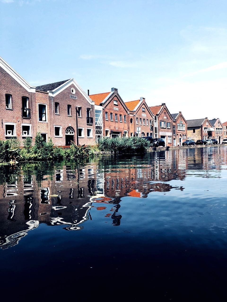 BUILDINGS BY LAKE AGAINST SKY