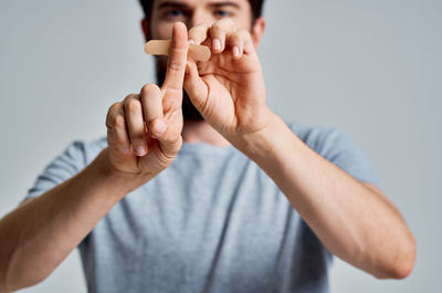 Midsection of man putting bandage on finger