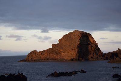 Rocky mountain and sea against sky