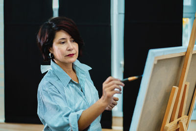 Woman painting on canvas in studio