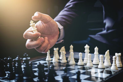 Midsection of businessman holding king chess piece above board