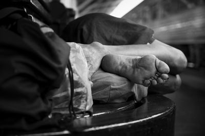 Low section of homeless person sleeping on bench