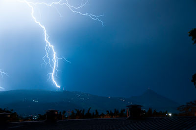 Lightning over mountains against sky at night