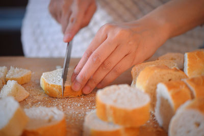 Midsection of woman cutting bread on table