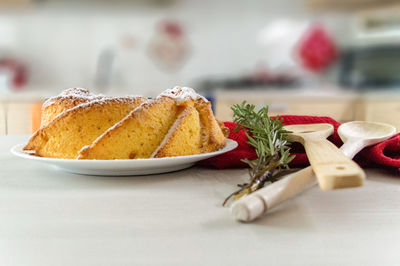 Close-up of christmas sponge cake on a kitchen table with wooden utensils and rosemary 