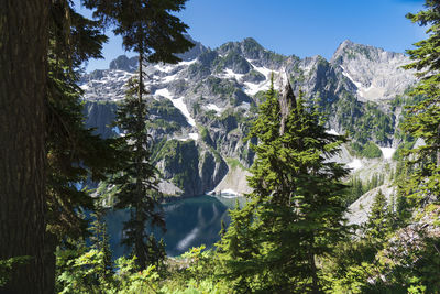 Looking through the trees at alpine lake and mountain ridge.