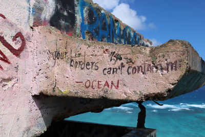 Close-up of text on rock against sky