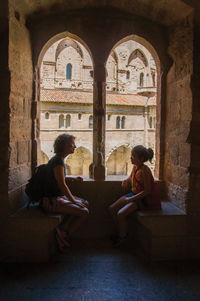 Woman sitting on archway of historic building