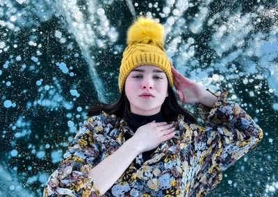 Portrait of young woman standing against waterfall