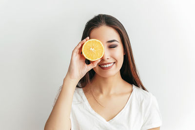 Portrait of young woman holding apple against white background