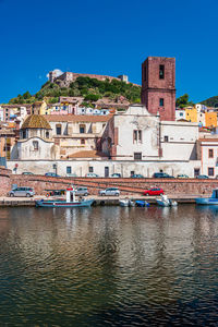 Buildings by river against clear blue sky