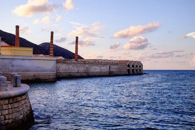 Built structure by sea against sky