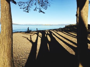 Silhouette people on beach against clear sky