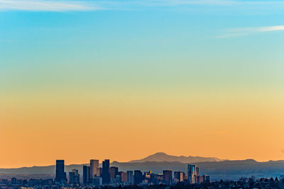 Buildings in city against clear sky during sunset